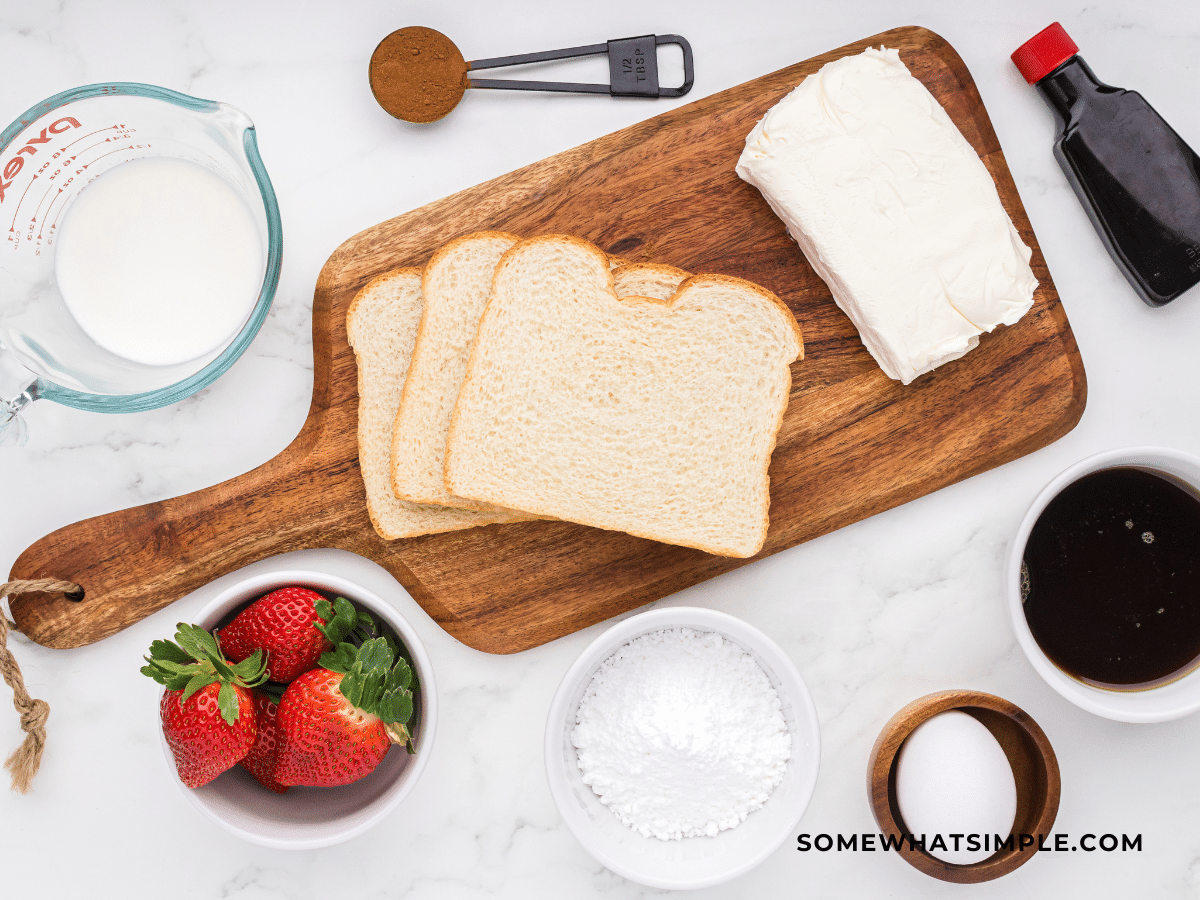 Ingredients to make French Toast Roll Ups laid on a counter with a wood cutting board