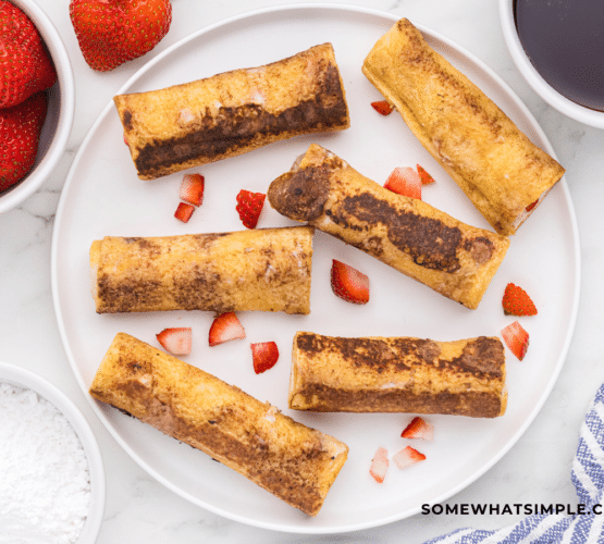 photo of French toast rollups on a white plate with strawberries