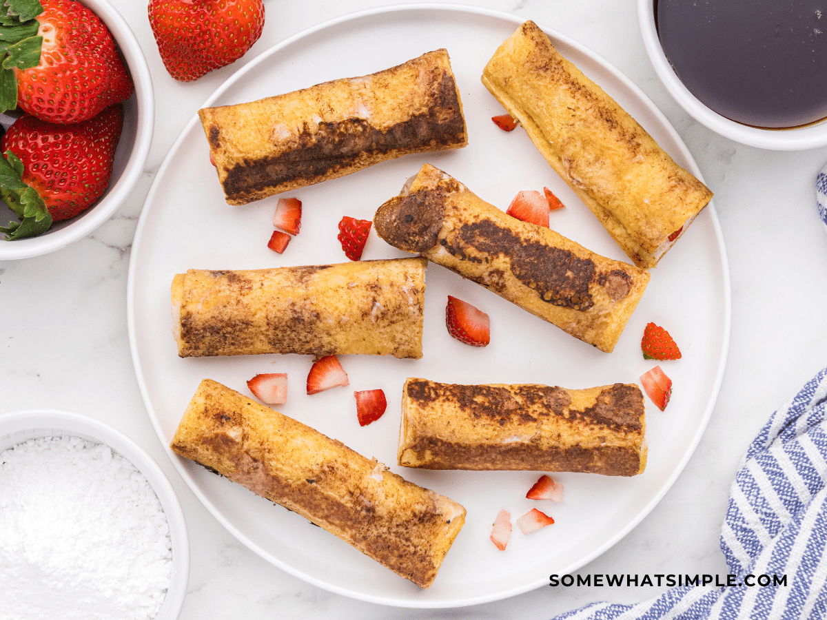 photo of French toast rollups on a white plate with strawberries