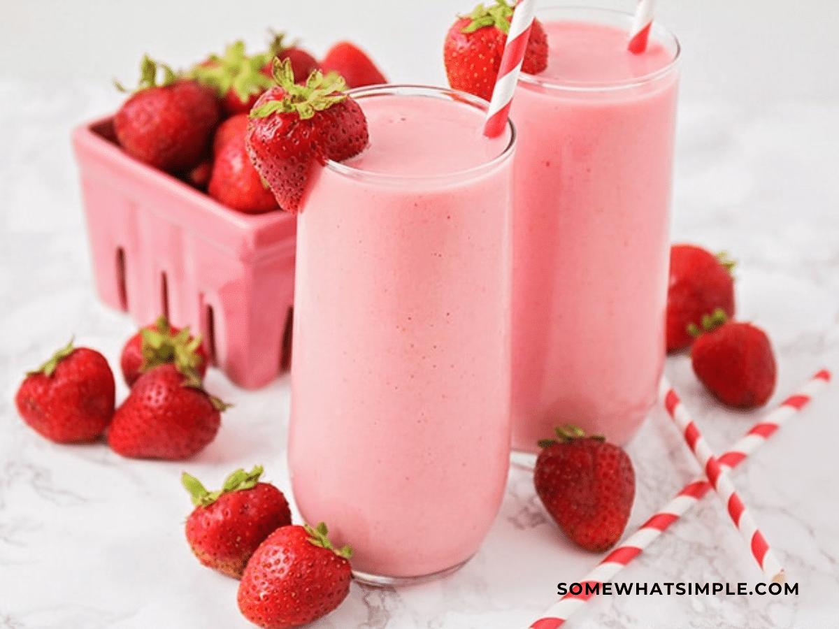 Finished Product of Strawberry Julius in glass cup with strawberries around it