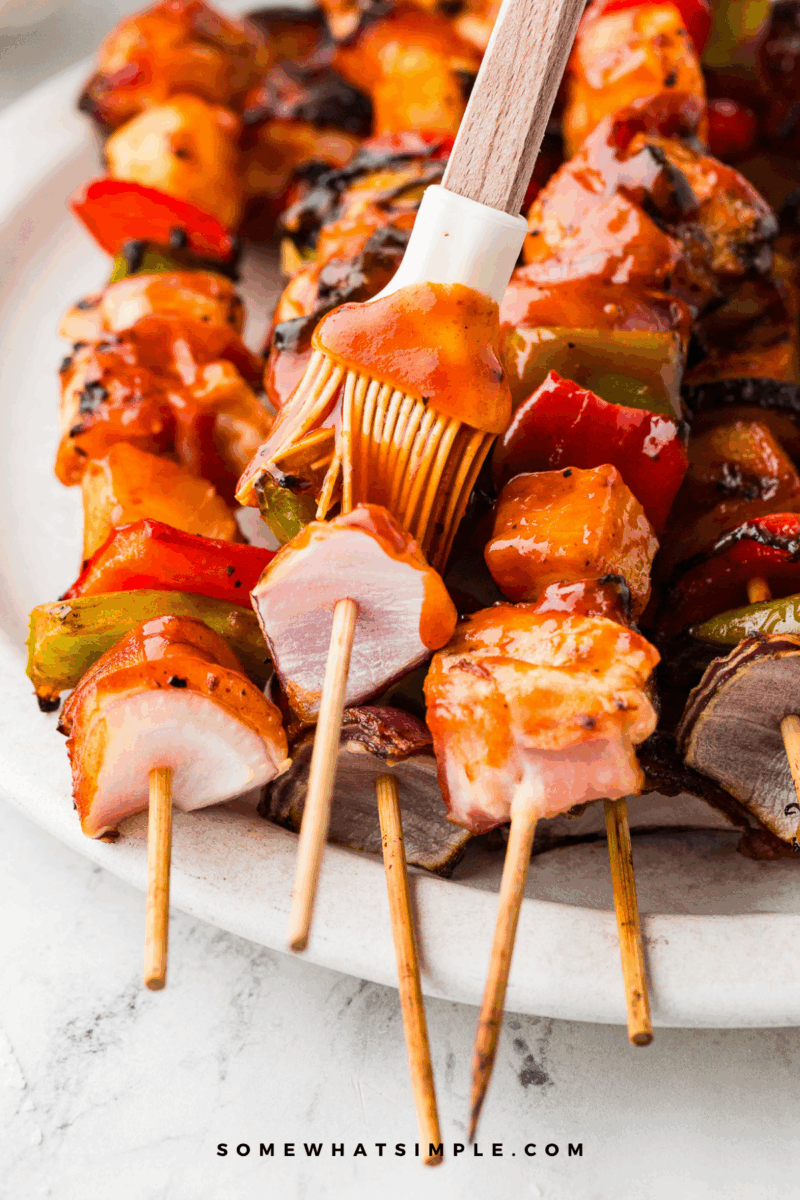 brushing bbq sauce on Hawaiian Bacon-Wrapped Chicken Kabobs