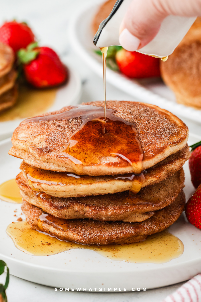 syrup being poured on a stack of churro pancakes