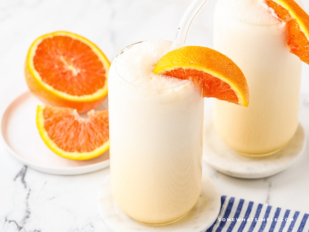 2 glasses filled with orange julius' and sliced oranges
